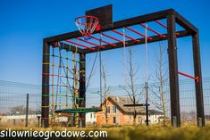 a basketball hoop in the middle of a fenced area with a house behind it