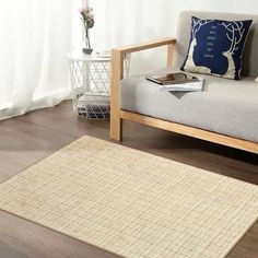 a living room with a couch, chair and rug on the wooden floor next to a window