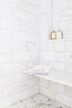 a bathroom with white marble walls and flooring that has hexagonal tiles on the wall