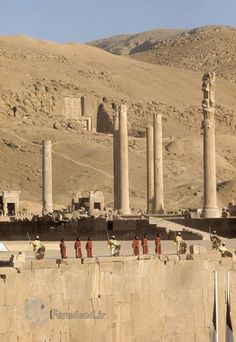 some people are standing on the side of a wall in front of an ancient city