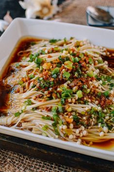 a white dish filled with noodles and vegetables