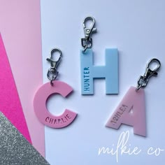 three key chains with the letters h, c, and h on them sitting next to each other