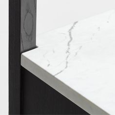 a white marble counter top next to a black metal frame and wooden door with an abstract design on it