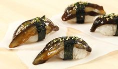 four pieces of sushi with sauce and sesame seeds