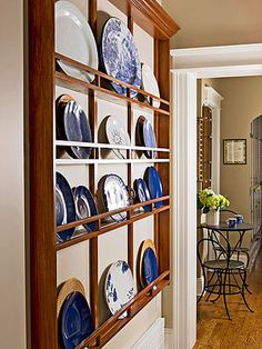 a wooden shelf filled with blue and white plates on top of a hard wood floor