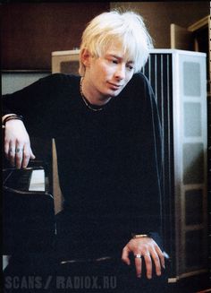 a man with blonde hair sitting at a piano