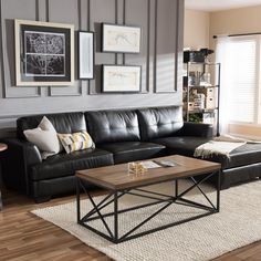 a living room with black leather couches and pictures on the wall above it's coffee table