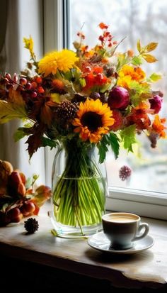 a vase filled with flowers next to a cup of coffee on a window sill