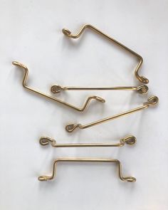 four brass metal hooks on a white background