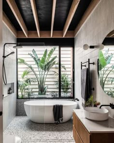 a bathroom with two sinks and a bathtub in the middle, surrounded by plants