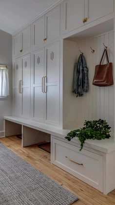 a room with white cupboards and wooden flooring next to a rug on top of a hard wood floor