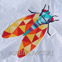 a close up of a colorful insect on a piece of paper with the words quilting impossible written below it