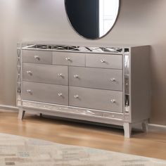 a silver dresser sitting next to a mirror on top of a wooden floor