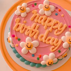 a pink birthday cake with flowers and smiley faces on the frosting that says happy birthday