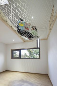 an empty room with a net hanging from the ceiling, and two children playing in it