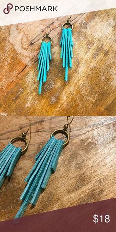 two pairs of earrings with blue tassels on wooden table next to postcard for poshmark