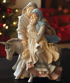 a nativity figurine on a table with a christmas tree in the background