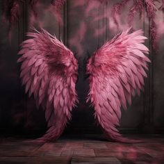 two large pink angel wings sitting on top of a wooden floor in front of a wall