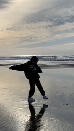 a person standing on the beach with their arms outstretched