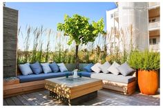 an outdoor living area with couches, tables and potted plants on the deck