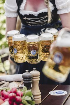 a woman is pouring beer into four glasses