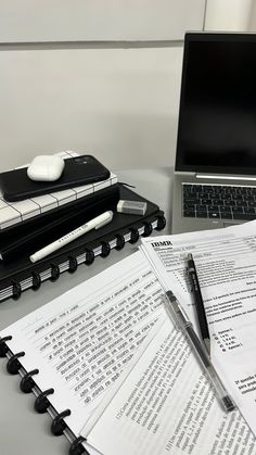 an open laptop computer sitting on top of a desk next to papers and headphones