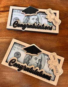 two graduation money clips with the words congratulations and one dollar bill cut out on them