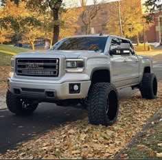 a silver truck is parked on the side of the road with leaves all over it