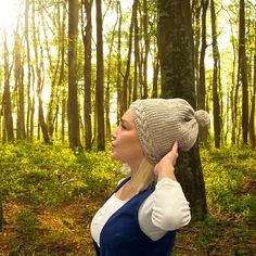 a woman standing in the woods wearing a knitted hat