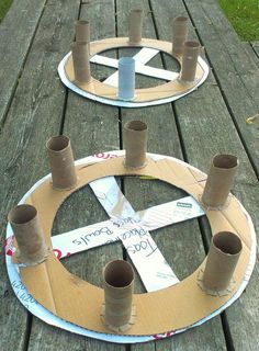 two cardboard circles with tape wrapped around them on a wooden table outdoors, one is made out of cardboard and the other has rolled up paper tubes