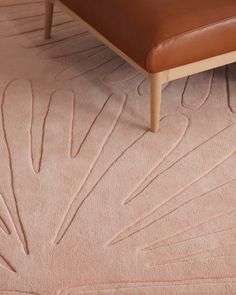 a brown leather bench sitting on top of a pink rug