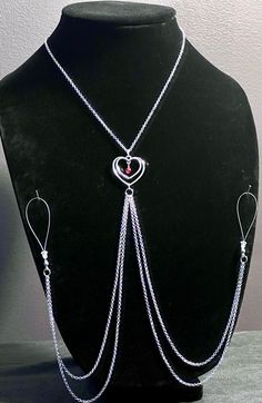 a black mannequin with silver chains and heart shaped pendants on it's neck