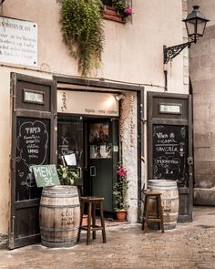 the outside of a restaurant with two wooden barrels