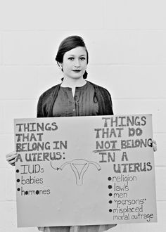 a woman holding up a sign that says things that belong in a uteros