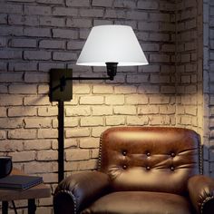 a lamp that is sitting on a table next to a chair in front of a brick wall