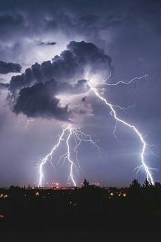 lightning strikes in the sky over a city at night with dark clouds and bright lights