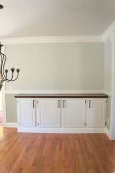 an empty room with white cabinets and wood flooring is pictured in this image, there are two chandeliers on either side of the wall