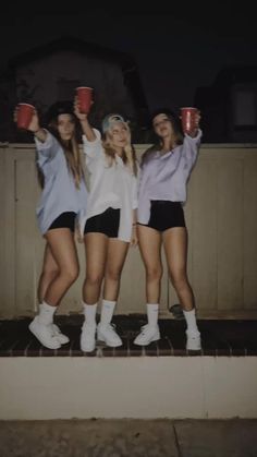 three girls are holding cups in their hands