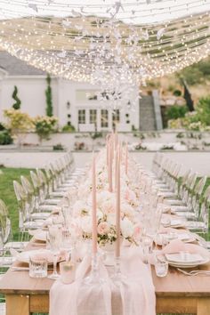 a long table is set with candles, plates and napkins for an elegant dinner