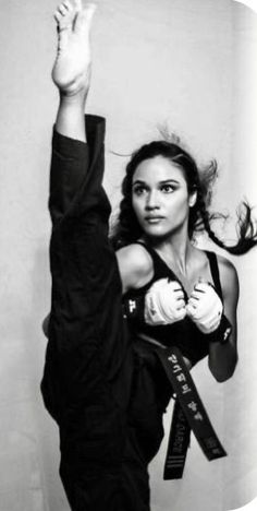 a woman in black shirt doing a handstand with her arms stretched out and one hand raised above her head