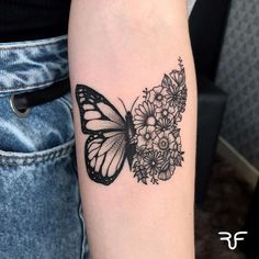 a black and white butterfly with flowers on it's back arm, sitting on a woman's left arm