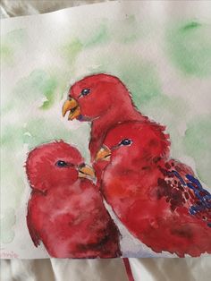 two red birds are standing next to each other on a piece of white paper with watercolor paint