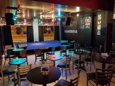 an empty restaurant with tables and chairs in the center, lit up by colorful lights