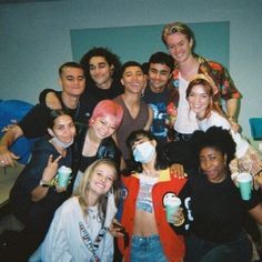 a group of young people standing next to each other holding coffee cups and wearing face masks