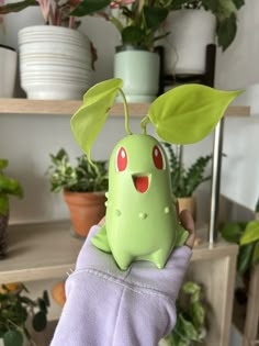 a person holding a green plant with red eyes in front of some potted plants