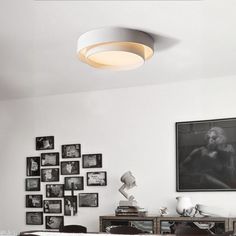 a living room with white walls and pictures on the wall, including an oval light fixture