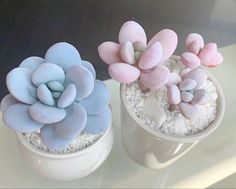 three small pots with fake flowers in them on a window sill, one is blue and the other is pink