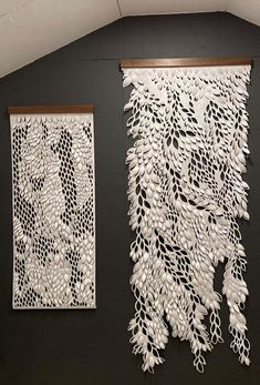 two white wall hangings on the side of a black wall next to each other