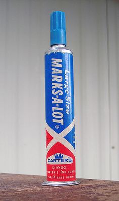 a blue and red spray bottle sitting on top of a wooden table next to a white wall