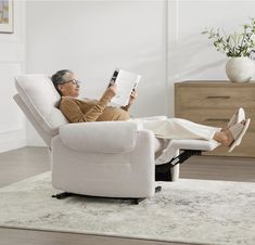 an older woman sitting in a recliner reading a book